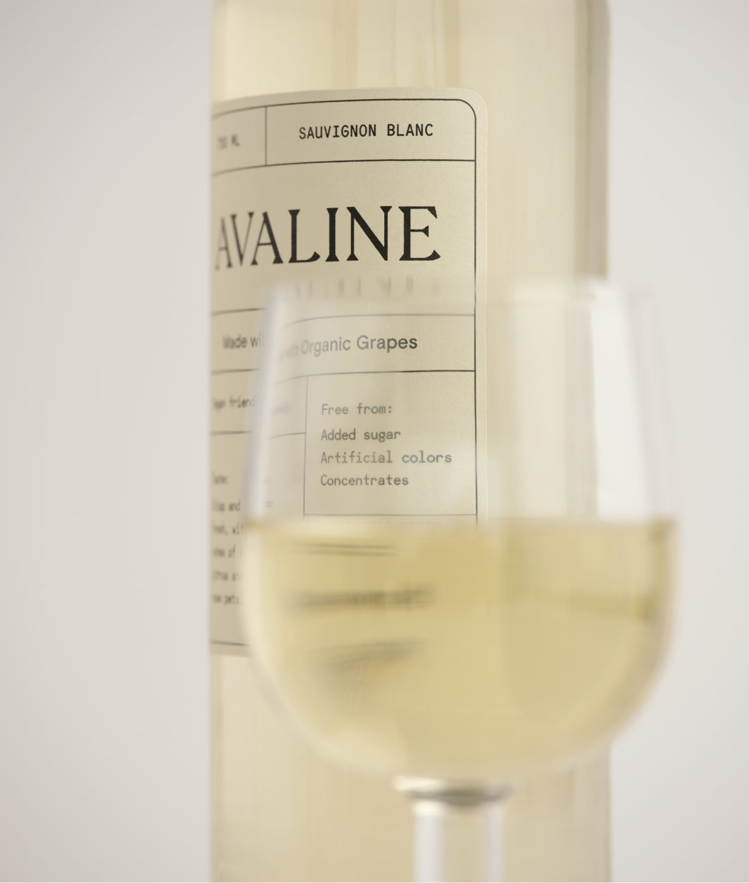 Side image of bottle of Sauvignon Blanc with a glass of wine in front of the bottle