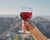 A woman holding a glass of Avaline Red with mountains in the background