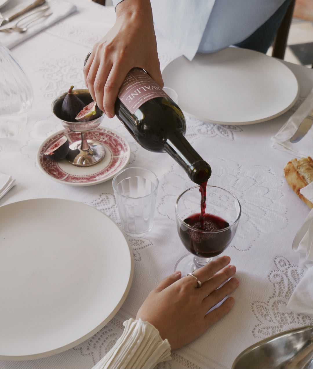 A bottle of Avaline Cabernet Sauvignon being poured into a wine glass on a dinner table