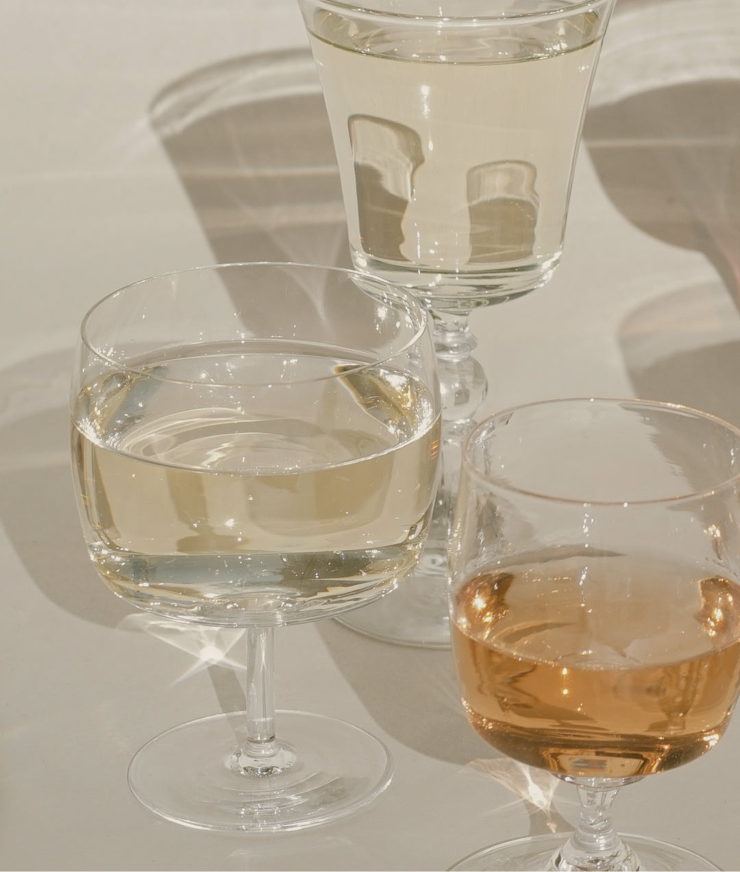A closeup image of three wine glasses filled with Avaline White, Rosé, and Sparkling on a white table.