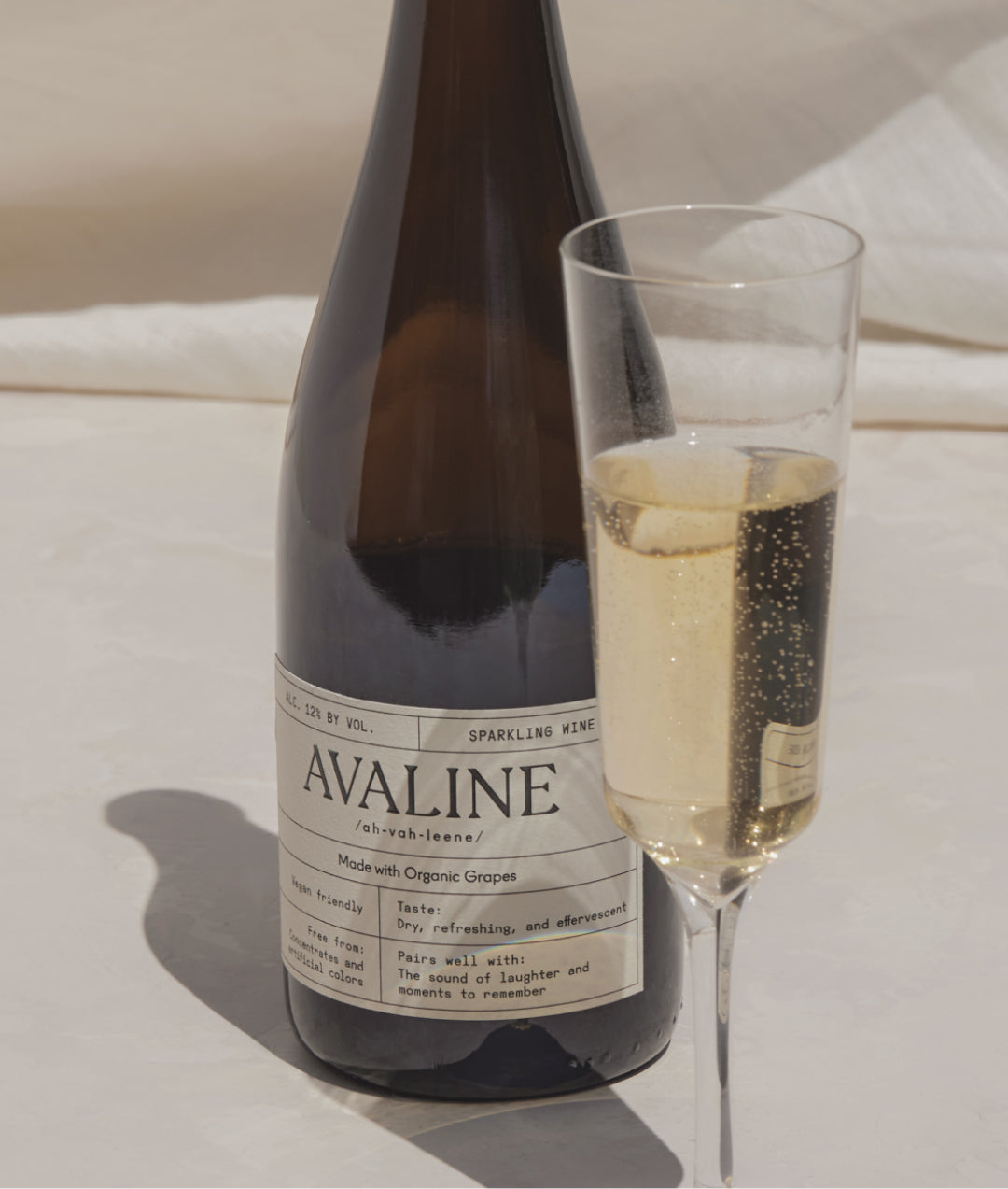 Bottle of avaline sparkling next to a full class 